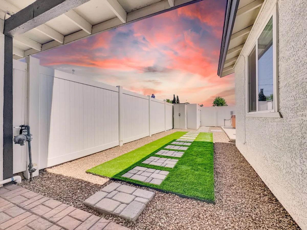 A peaceful outdoor pathway winds through a green lawn bordered by a fence, set beneath a wide, open sky. The scene suggests an inviting spot for evening strolls or play, mirroring the sense of relaxation and exploration that comes after a day of local adventures.