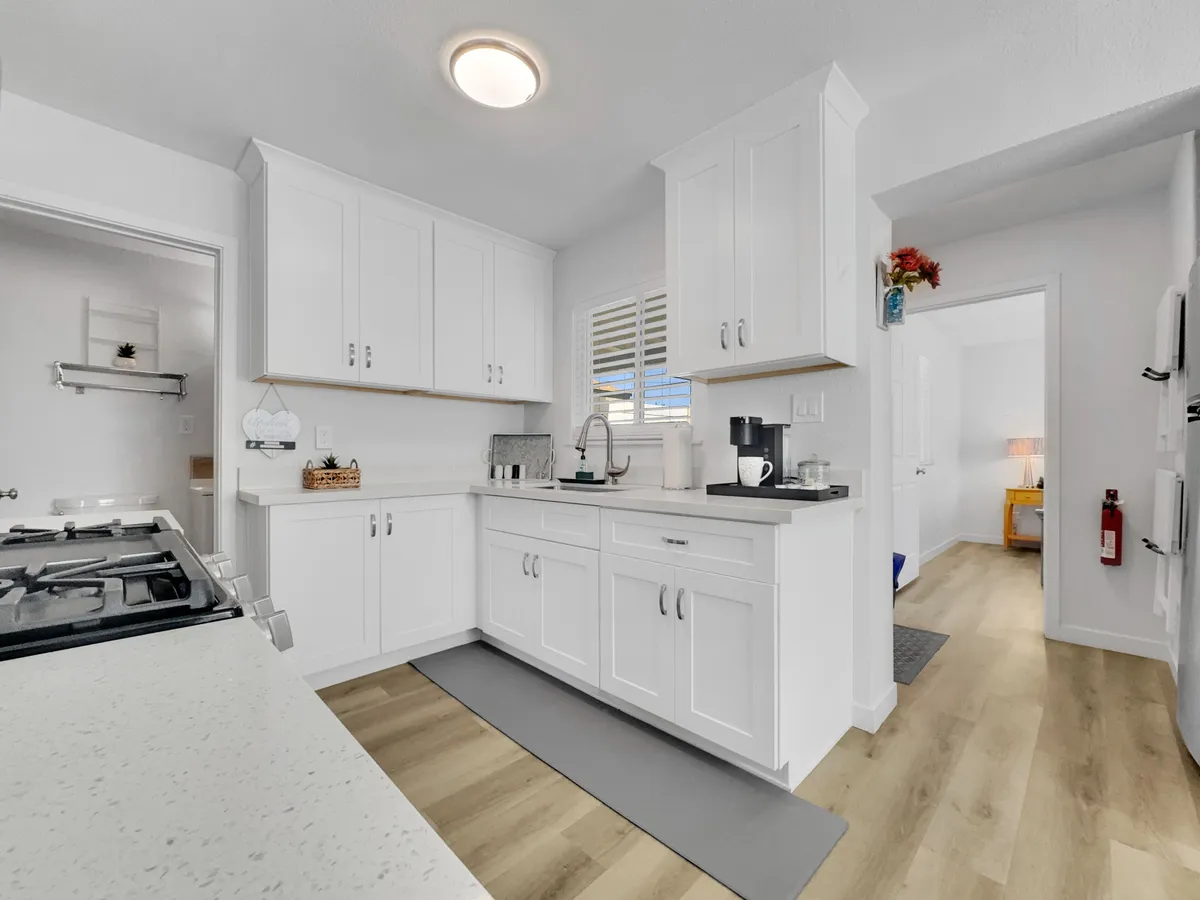 A spacious kitchen with white cabinetry, gleaming stainless steel appliances, a functional kitchen island, and a dedicated coffee station. Natural light pours through a window, brightening the workspace and creating an inviting atmosphere ideal for meal preparation or a morning coffee ritual.