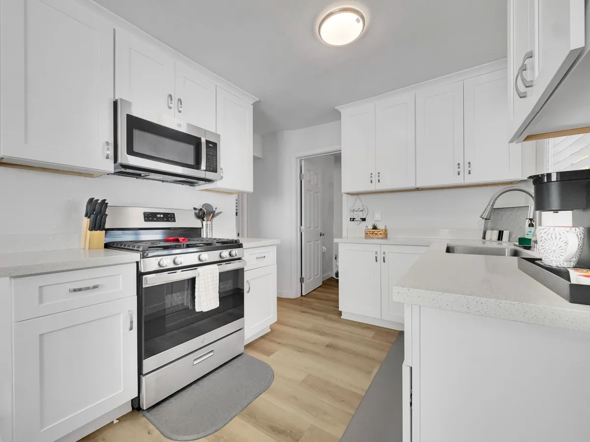 A bright, functional kitchen featuring a modern stainless steel stove, white cabinetry, and ample countertop space. The atmosphere is welcoming and practical, with hints at communal or individual meal preparation and entertaining guests.